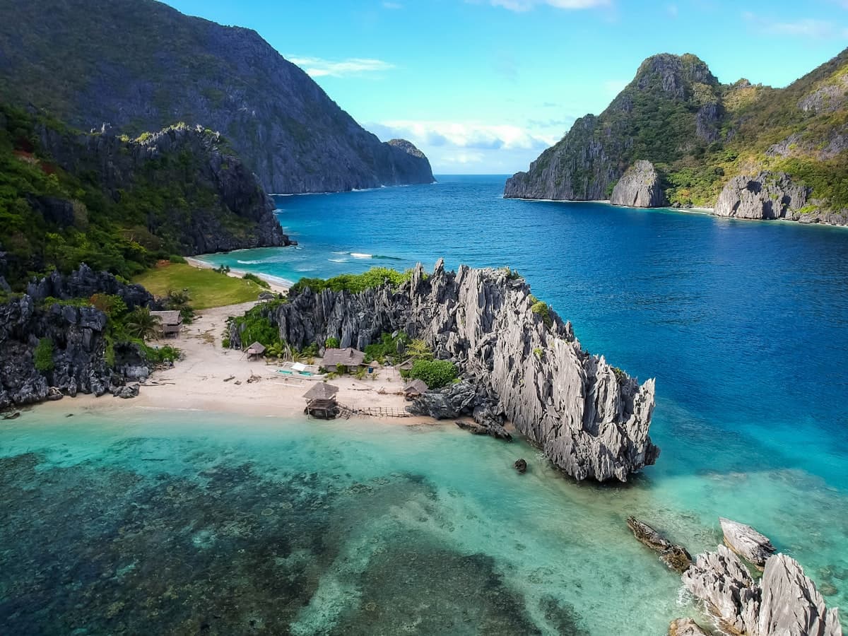 White sand beach with turquoise water and limestone cliffs on Entalula Island in El Nido Palawan