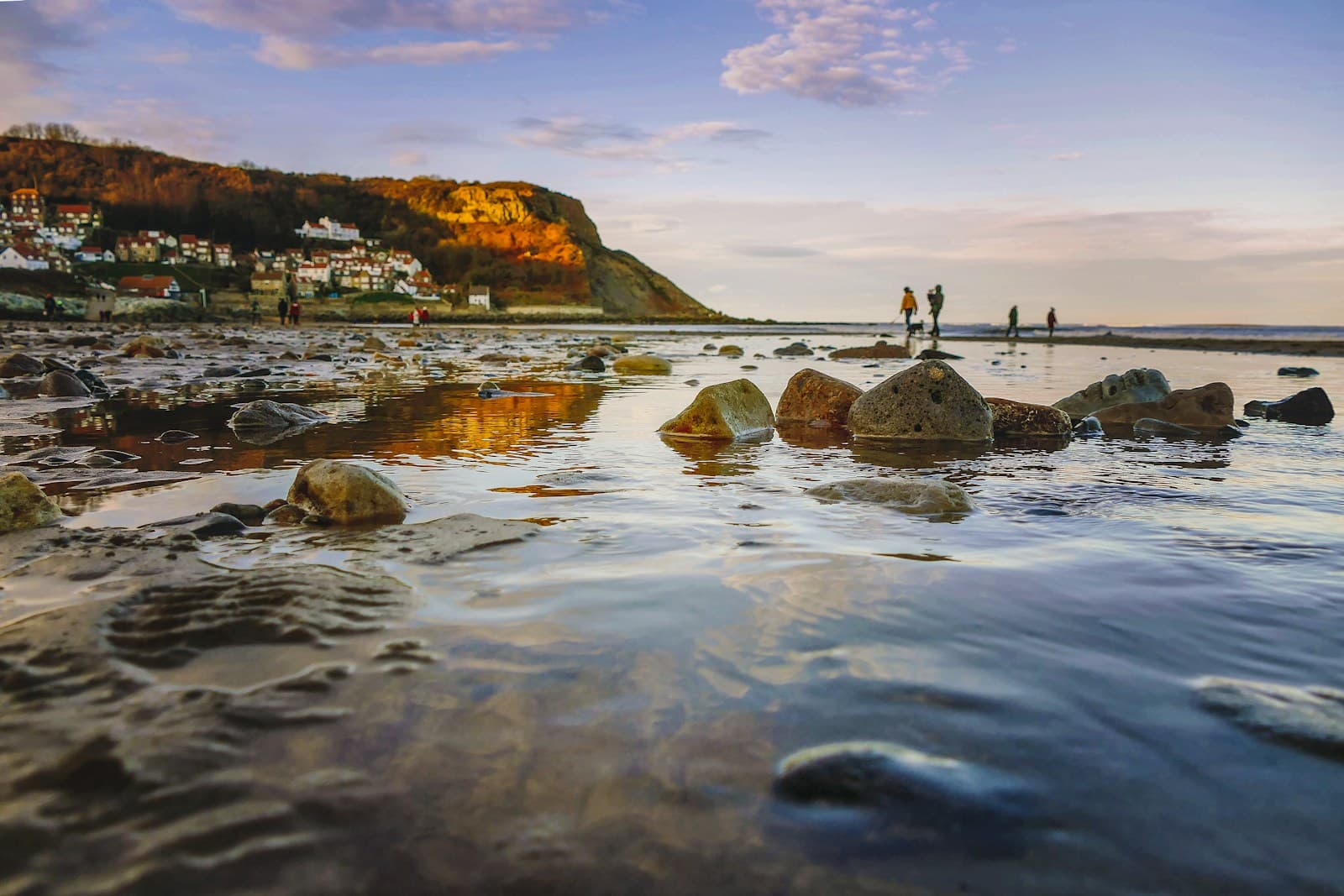 Rocky foreshore at low tide near Kettleness on the North Yorkshire coast with cliffs and village in the background