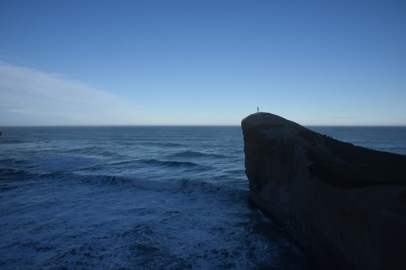 Dramatic sandstone headland at Tunnel Beach near Dunedin with rough ocean waves crashing below