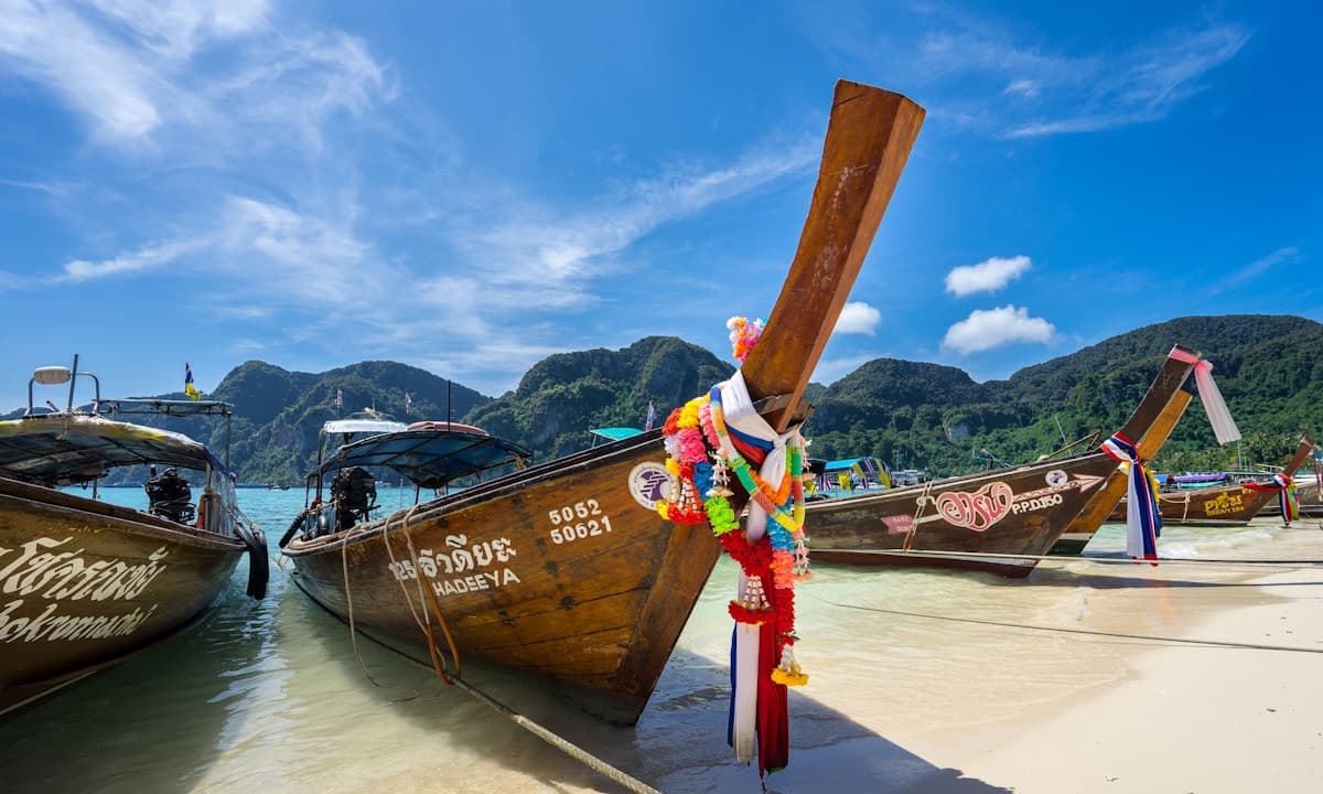 Longtail boats on clear turquoise water with limestone cliffs in Thailand