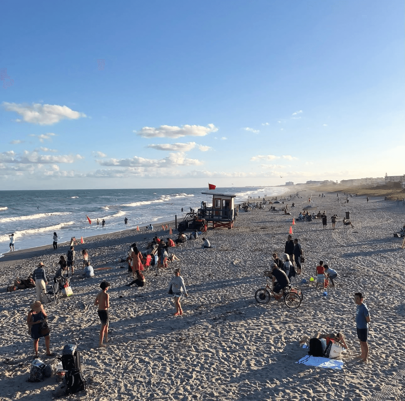 Cocoa Beach Pier extending into the Atlantic with people on the white sand beach below