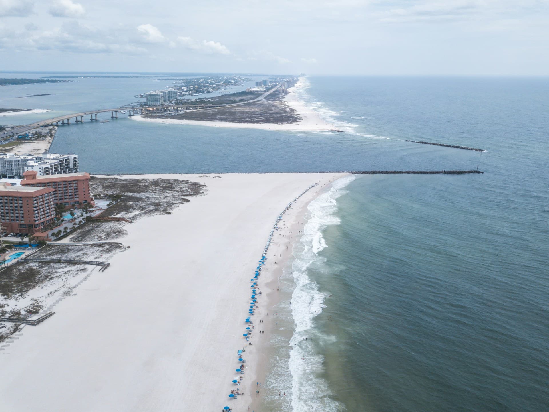 Turquoise waters and white sand at Orange Beach Alabama with a fishing pier in the background