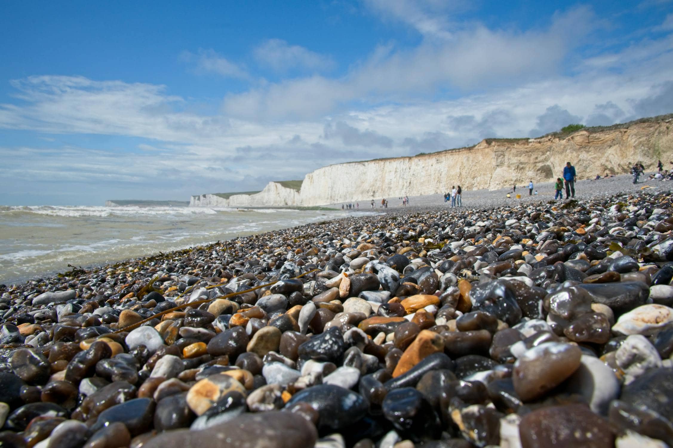 Pebble shoreline at Aldwick Beach looking west towards Pagham with calm sea and groynes