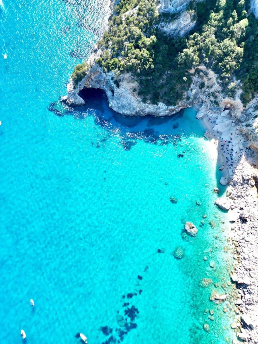 Crystal clear turquoise water at Cala Goloritzé beach with the dramatic limestone Aguglia pinnacle rising in the background