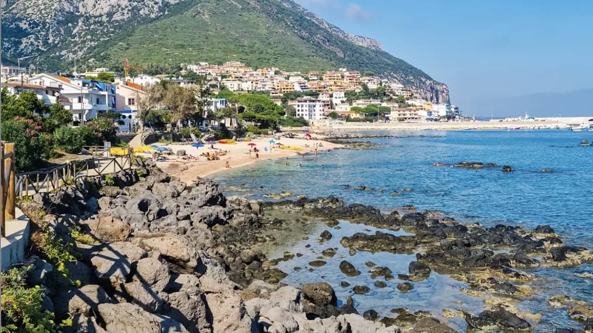 Cala Gonone Central Beach Sardinia with calm clear water, sandy shore, and the village behind