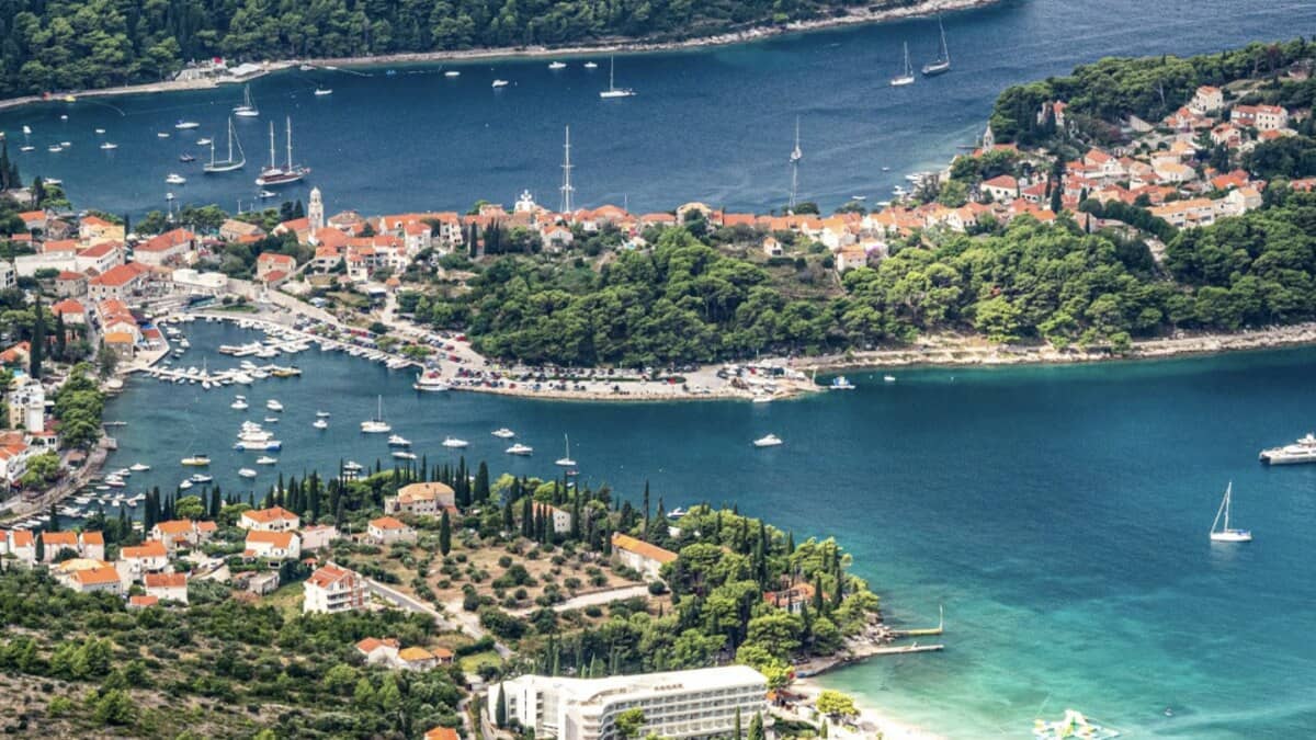 Aerial view of Cavtat near Dubrovnik, the wooded twin-bay peninsula with its yacht-filled harbour, orange-roofed old town and forested headlands beside the clear Adriatic