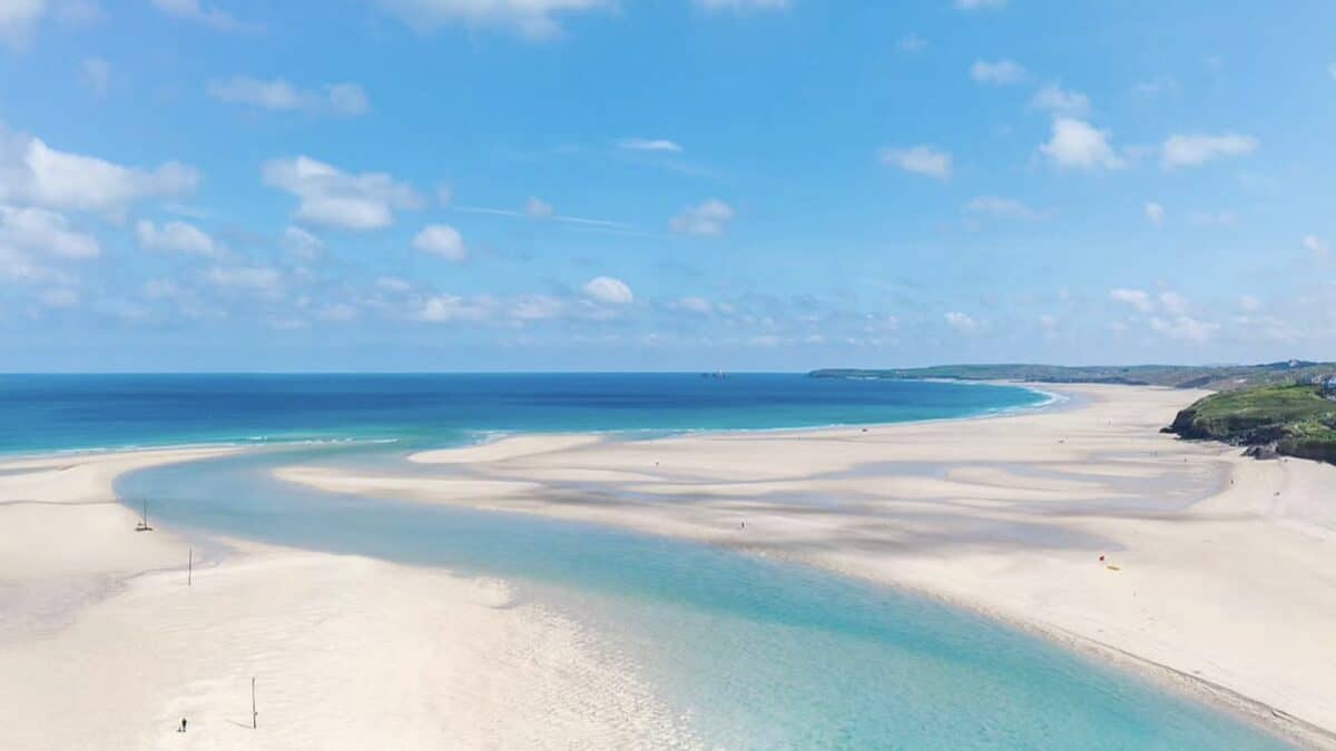 Wide low-tide view of Hayle Towans beach curving along St Ives Bay with marram dunes behind and a big Atlantic sky