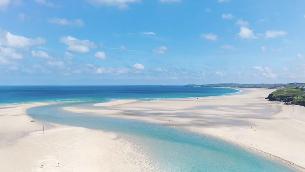 Wide low-tide view of Hayle Towans beach curving along St Ives Bay with marram dunes behind and a big Atlantic sky