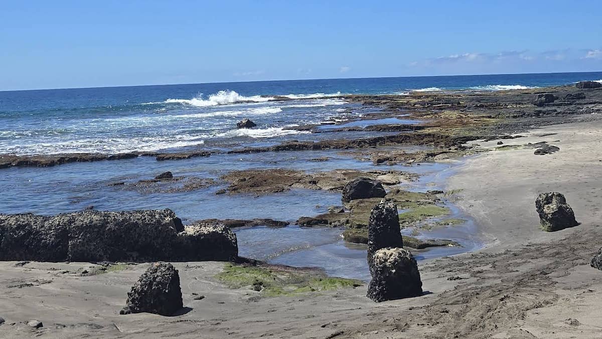 Ho'okena Beach Park Big Island south Kona with black sand, calm bay, and the fishing village in the background