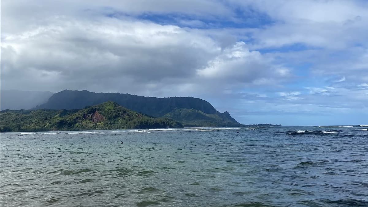Pu'u Poa Beach below the Princeville bluff with the reef-protected lagoon and view across Hanalei Bay