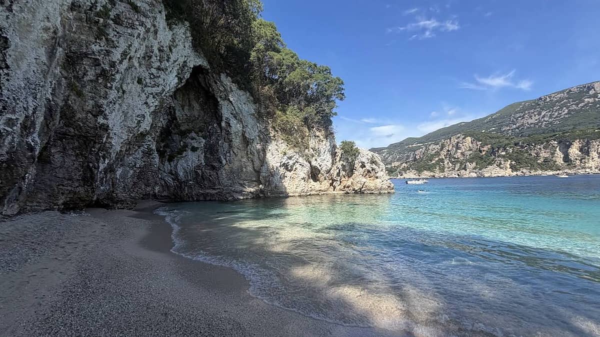 Rovinia Beach Corfu with the white pebble cove framed by limestone cliffs and clear deep turquoise water