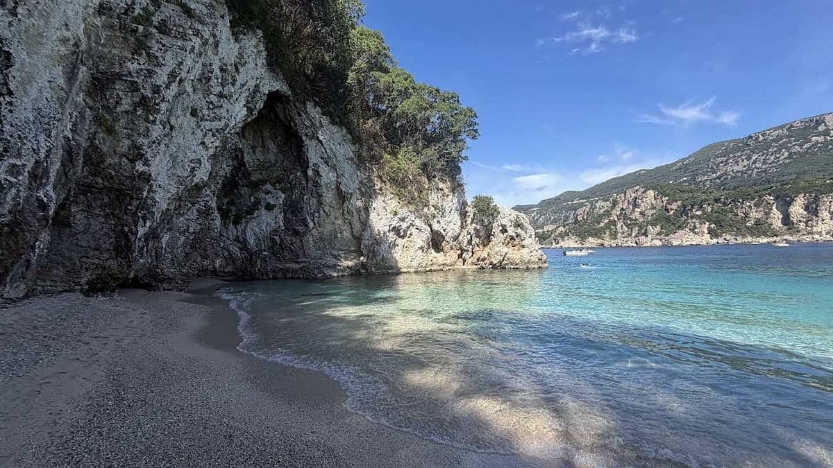 Rovinia Beach Corfu with the white pebble cove framed by limestone cliffs and clear deep turquoise water