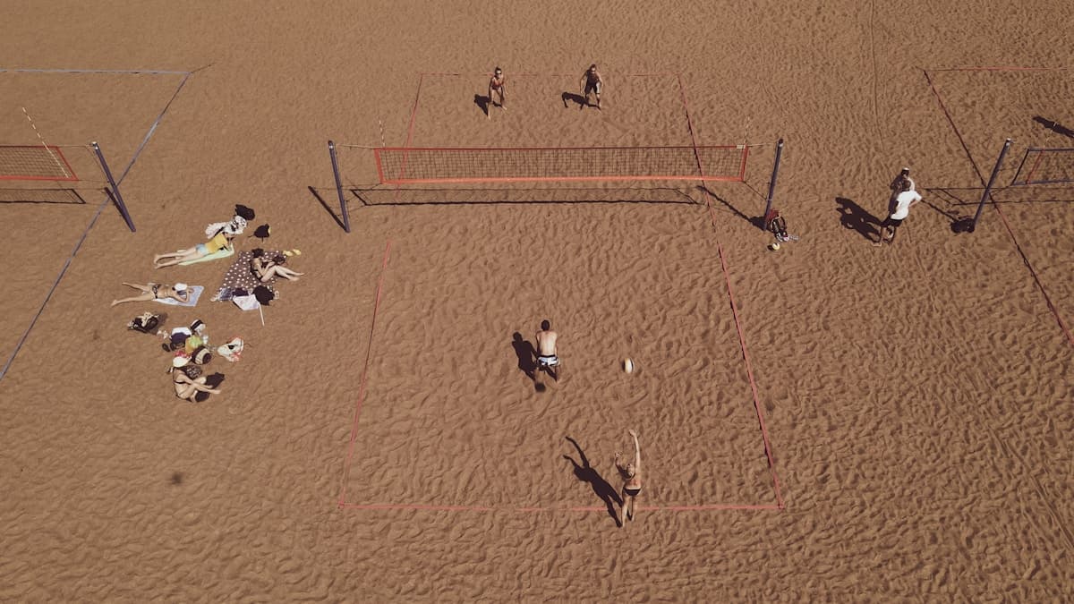 People playing beach games on sand with ocean in background