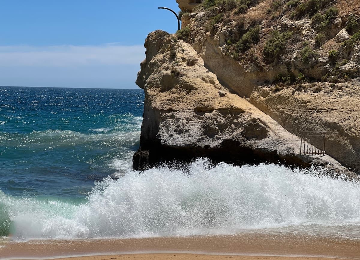 Clear turquoise water washing onto pale sand on a European Mediterranean coast in summer