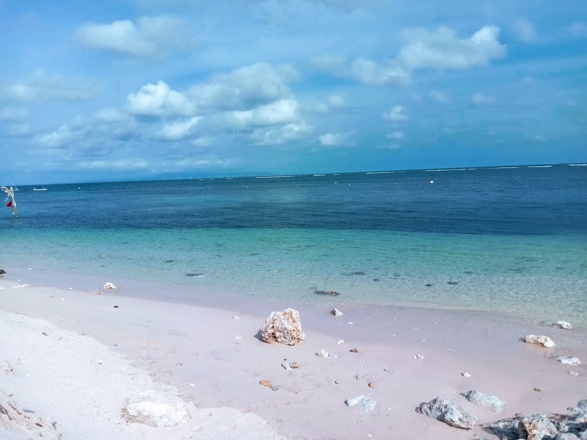 Dramatic cliffside view of a Bali beach with turquoise water and golden sand