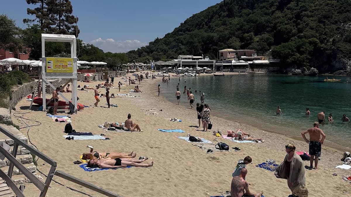 A sandy cove with a lifeguard tower, green headland and turquoise water at Paleokastritsa, Corfu