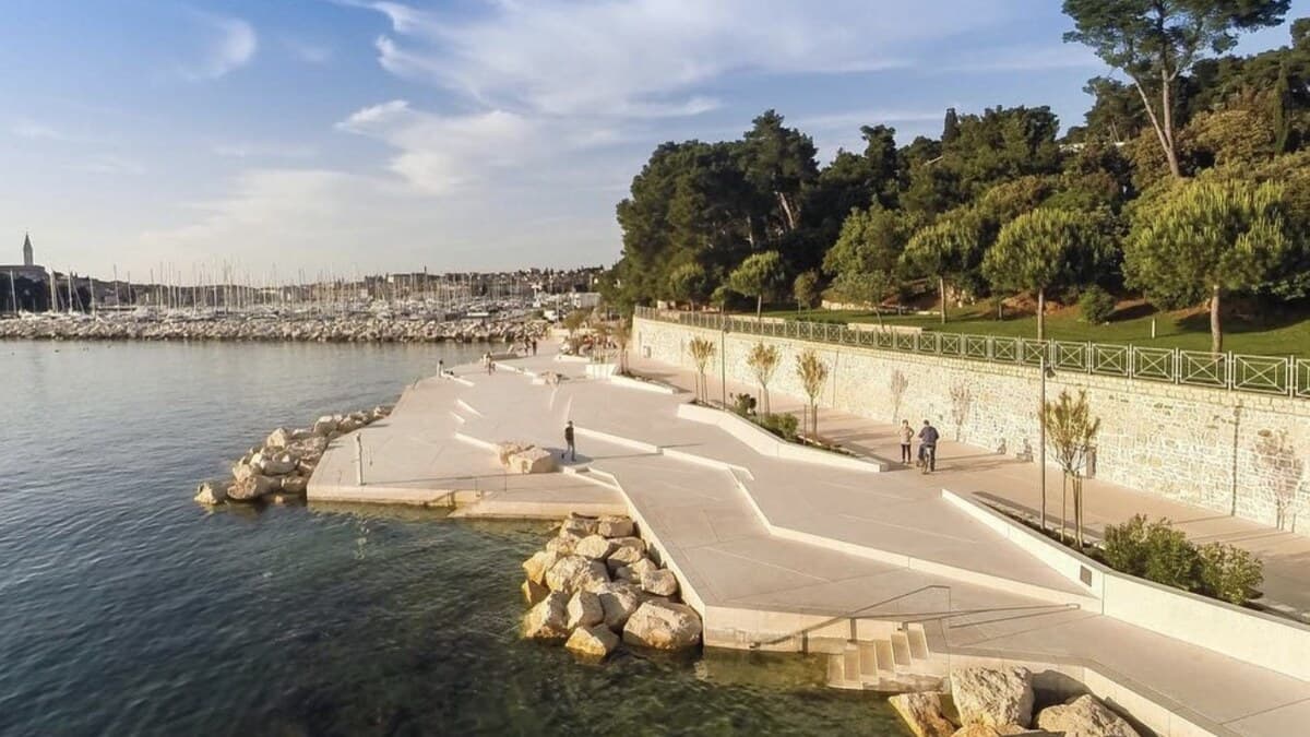 Mulini Beach in Rovinj, its concrete promenade beside the marina with St Euphemia's bell tower behind, on Istria's coast in Croatia