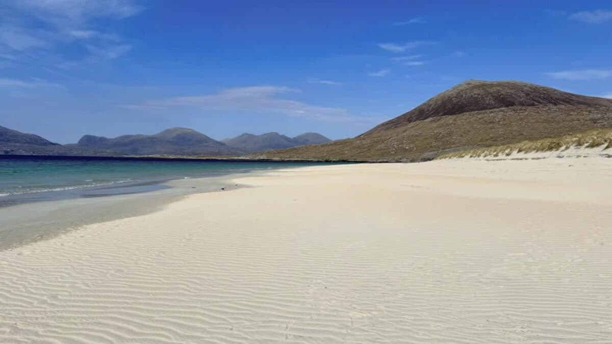 Luskentyre beach on the Isle of Harris, turquoise shallows over white shell sand with the green Harris hills behind on a clear day