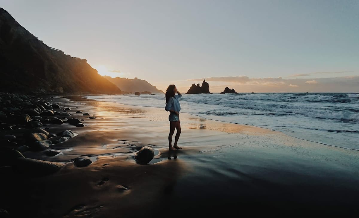 Black volcanic sand beach in northern Tenerife with dramatic waves and green cliffs