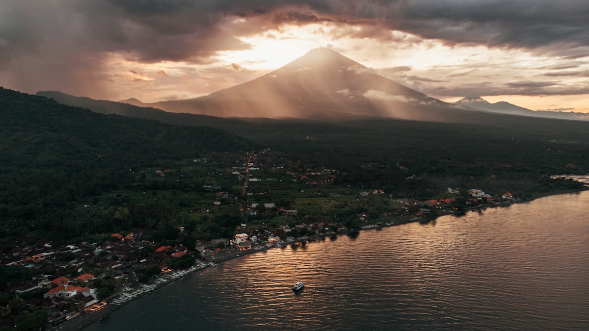 Black volcanic sand beach at Amed with traditional fishing boats and Mount Agung