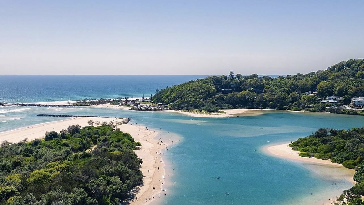 An aerial of Palm Beach on the Gold Coast where the creek mouth meets the sea, with sandbanks and a green headland