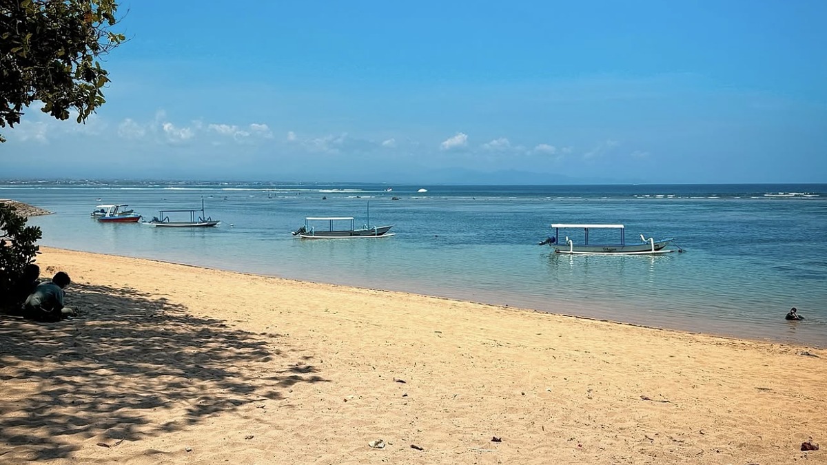Sanur Beach on Bali's east coast, calm reef-protected water and a paved beachfront path