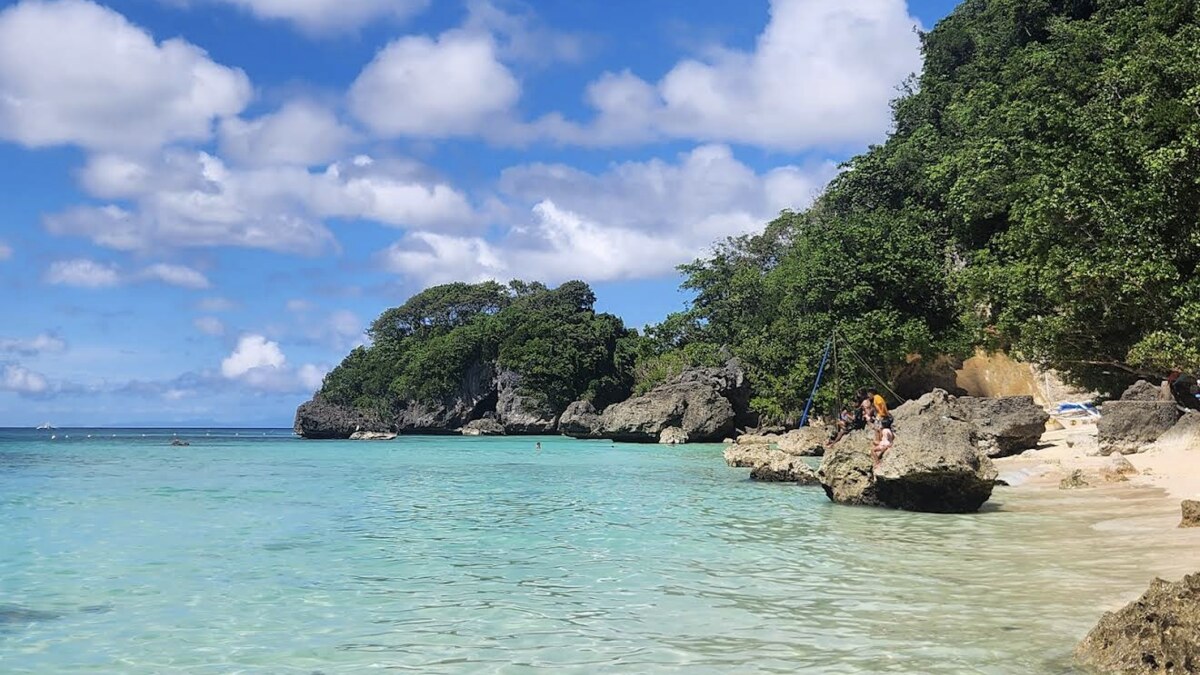Balinghai Beach on Boracay, a small cove of clear turquoise water framed by rocky outcrops and a forested headland