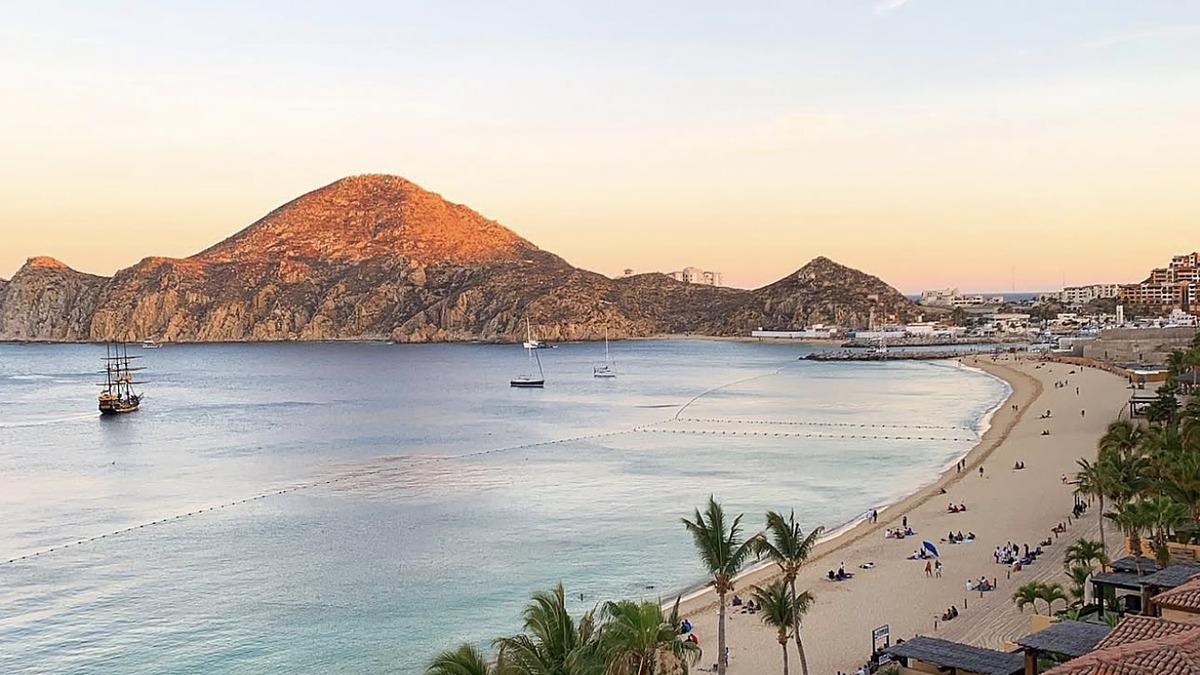 Medano Beach in Cabo San Lucas with calm Sea of Cortez water and the El Arco rock formation in the distance