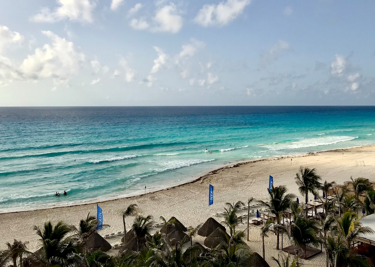 Wide white sand beach with turquoise waves at Playa Delfines Cancun