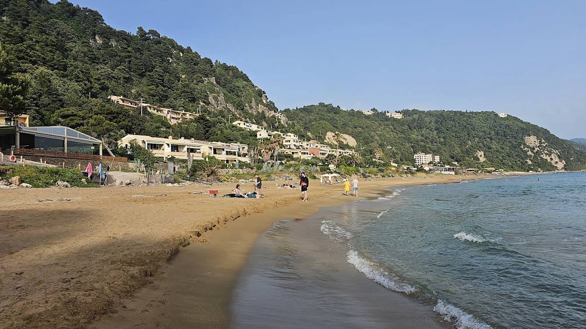 Glyfada Beach on Corfu's west coast, a long golden sand beach with resorts, loungers and cliffs at each end