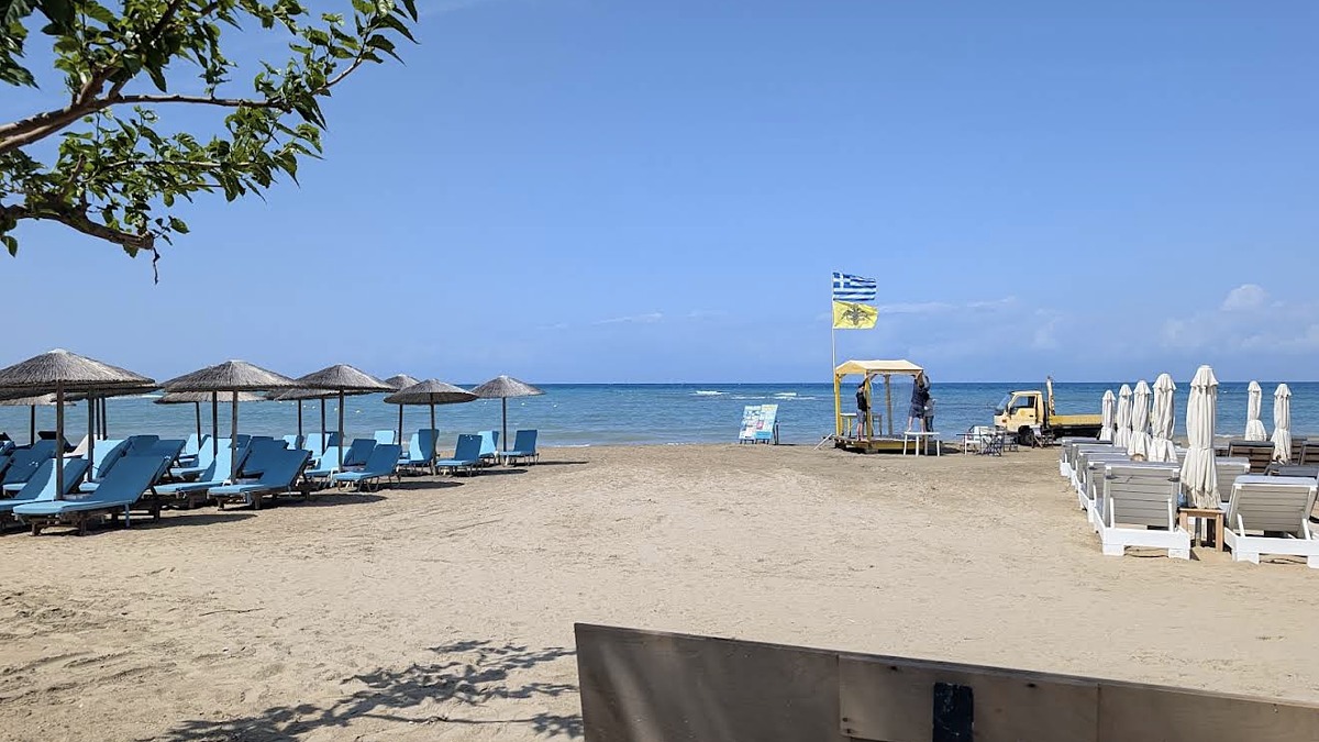 A sandy beach with sun loungers and a beach bar at Sidari on the northwest coast of Corfu