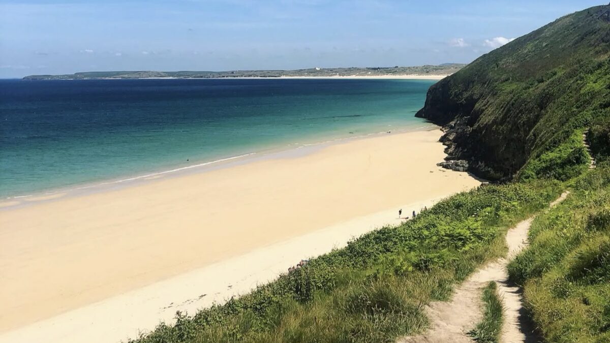 Carbis Bay's white sand and calm turquoise water in St Ives Bay, seen from the coast path with a green headland