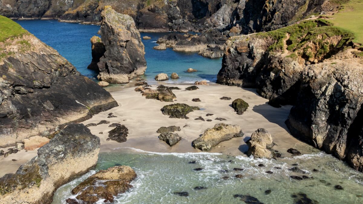 Kynance Cove at mid-low tide showing the caves and serpentine rock formations with the cafe path