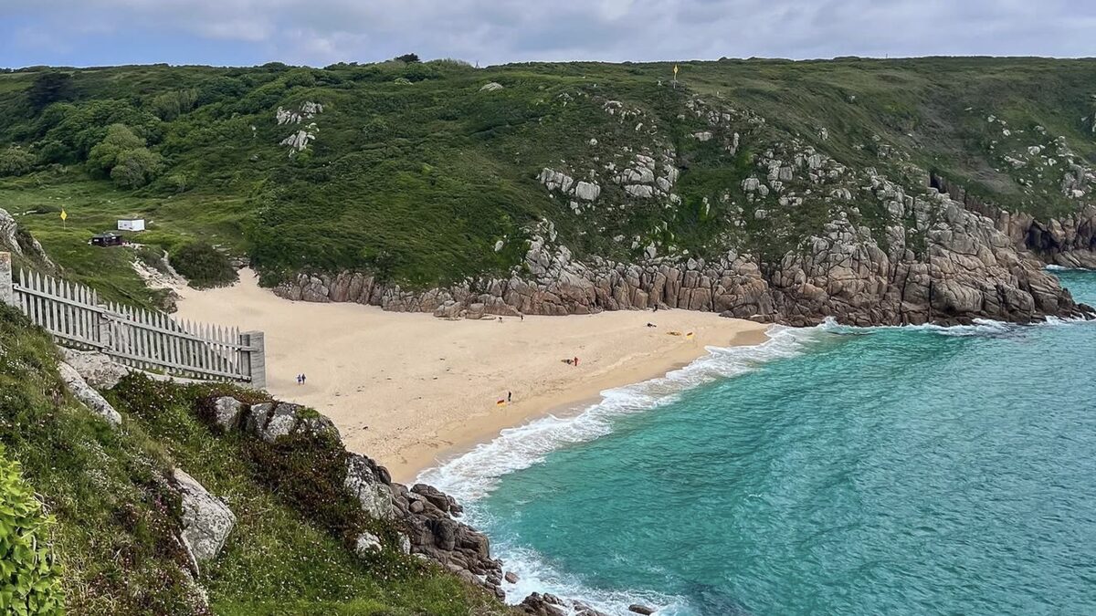 Porthcurno's white shell-sand beach and clear turquoise water below the granite cliffs near Land's End, viewed from the coast path