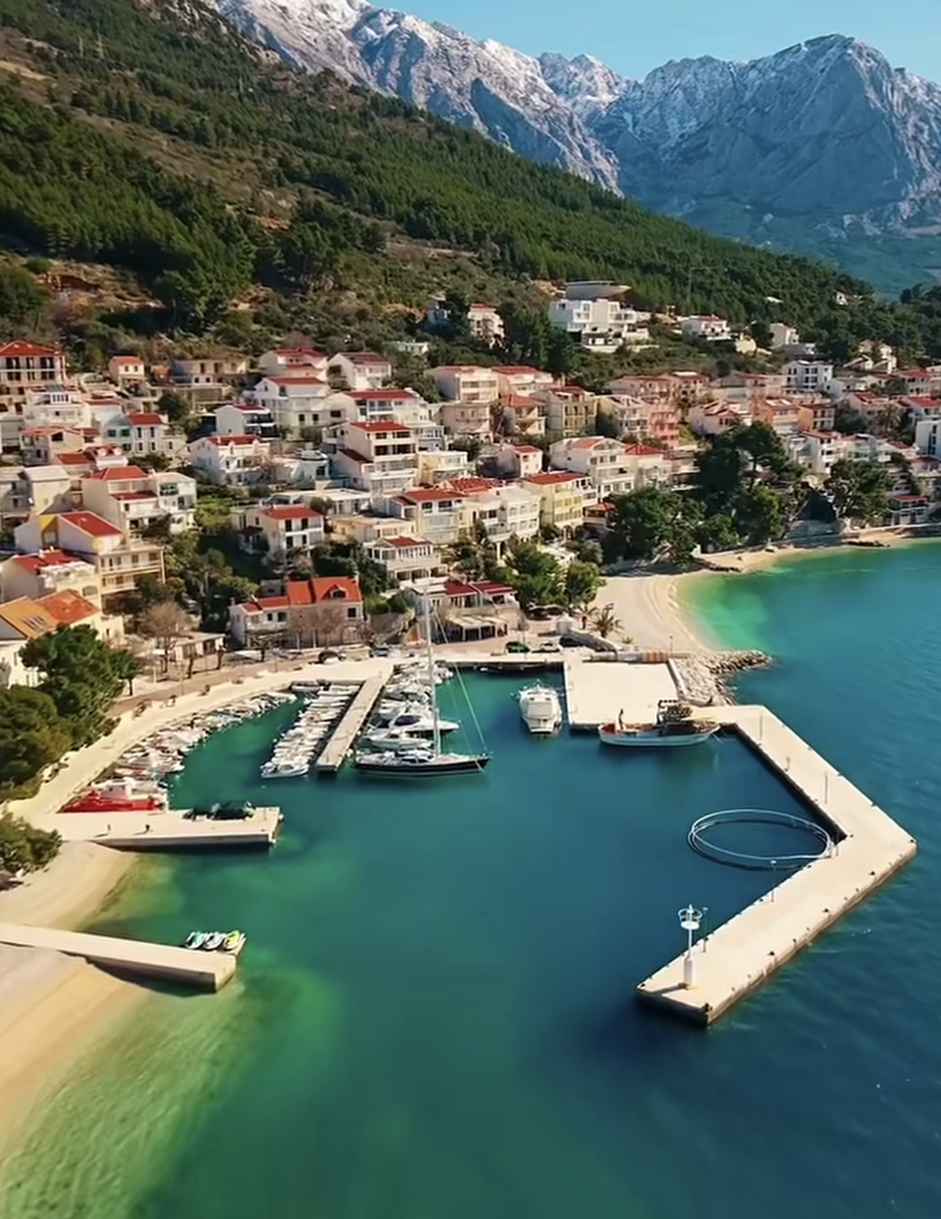 Punta Rata beach in Brela with pine trees and the Biokovo mountains behind