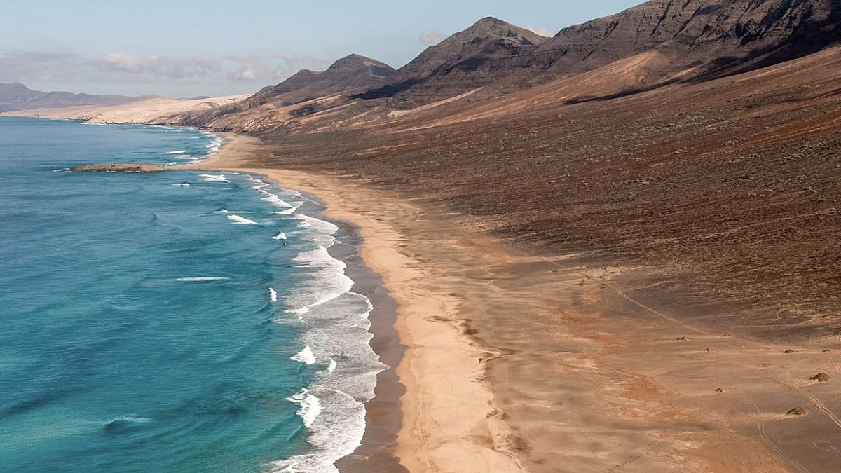 Playa de Cofete on the remote Jandia Peninsula, a wild 12km Atlantic beach beneath mountain ridges in Fuerteventura