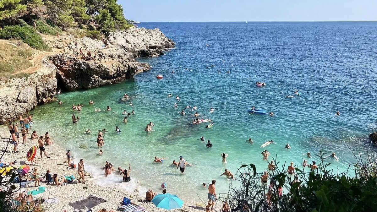 Hawaii Beach on the Verudela peninsula in Pula, a busy white-pebble cove of clear turquoise water backed by low limestone cliffs