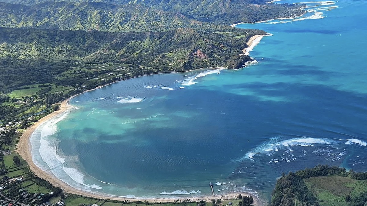 Hanalei Bay's crescent of sand with green mountains rising directly behind it