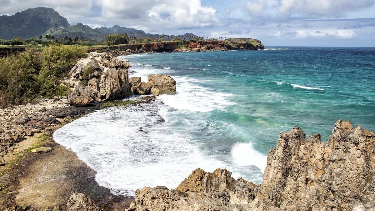 Maha'ulepu Beach with red-orange cliffs at one end and a wild empty stretch of sand