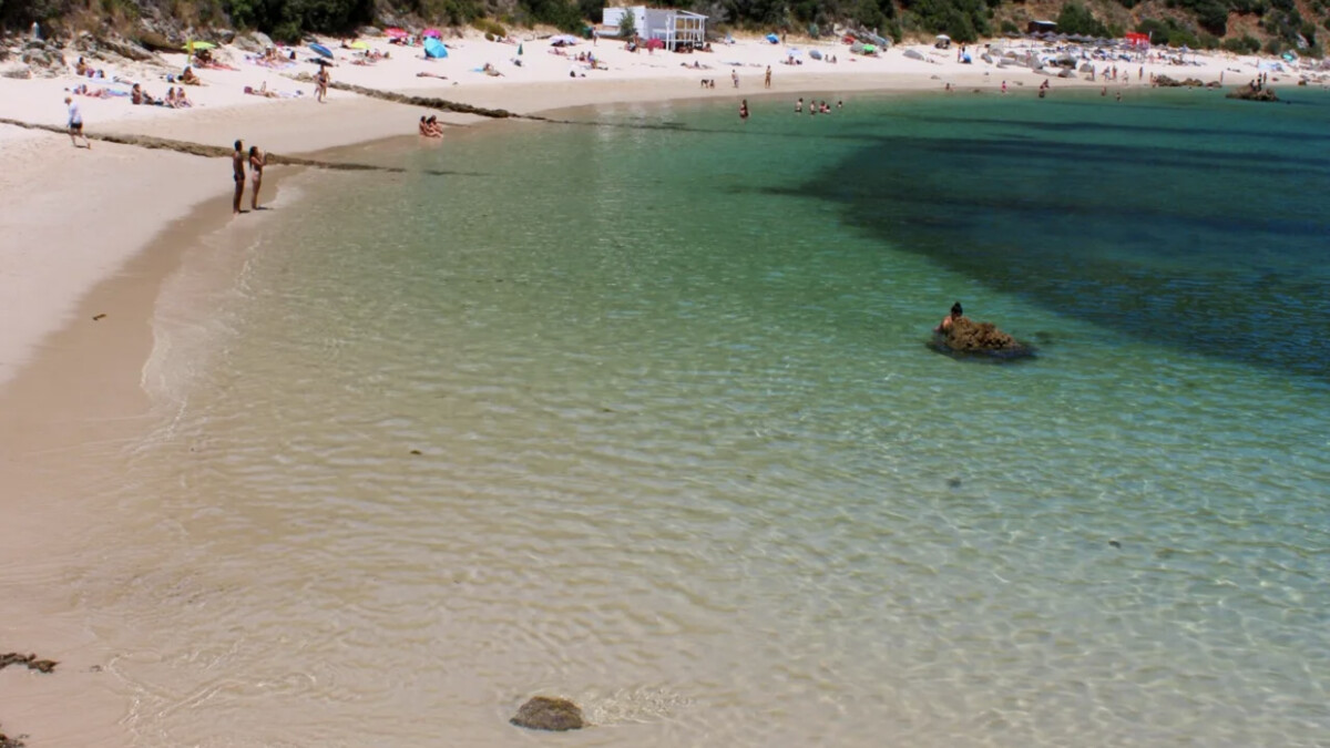 Galapinhos beach in Arrabida with near-transparent turquoise water and forested limestone cliffs