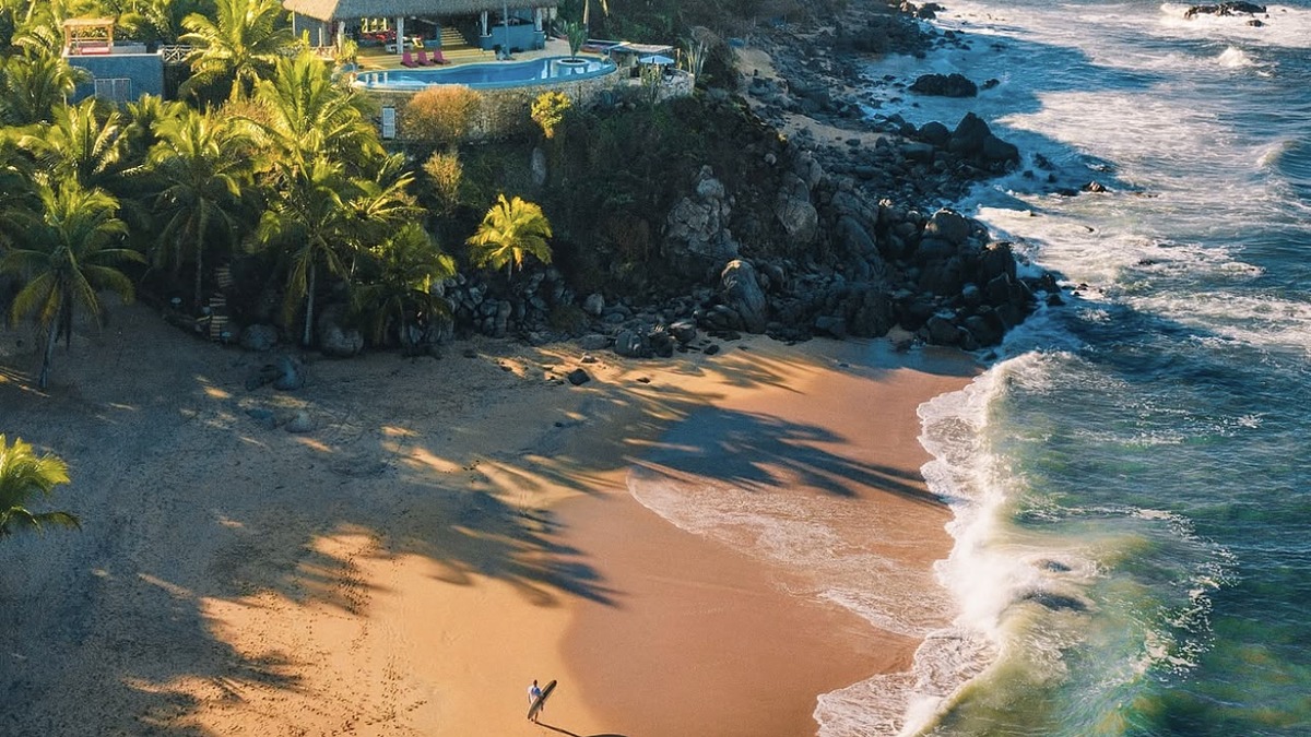 Sayulita Beach with surfers in the lineup and the colourful village behind