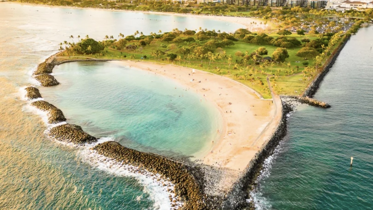 Ala Moana Beach Park with a calm lagoon and grass park behind the sand