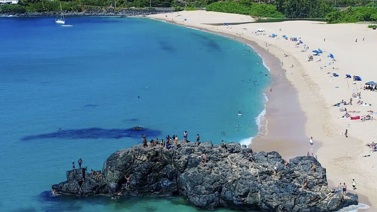 Waimea Bay's deep blue water with the cliff and jumping rock on the north side