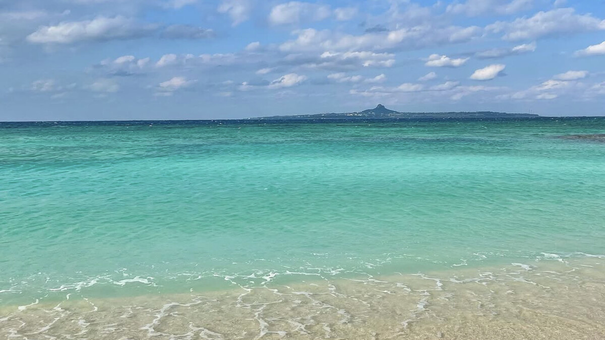 Emerald Beach beside Ocean Expo Park, calm clear shallow water with Ie Island and its Tacchu peak on the horizon
