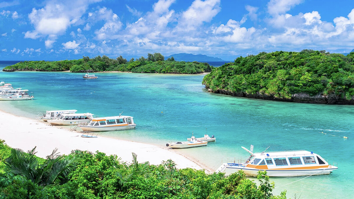 Kabira Bay on Ishigaki from the viewpoint, emerald-green water with scattered green islets and moored glass-bottom boats