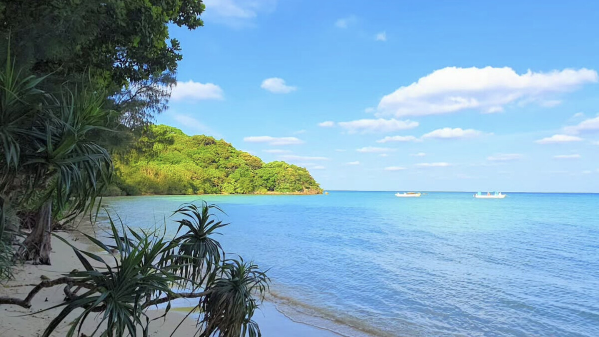 Sukuji Beach on Ishigaki, a kilometre-long shallow fine-sand bay with very calm clear water looking toward small offshore islands