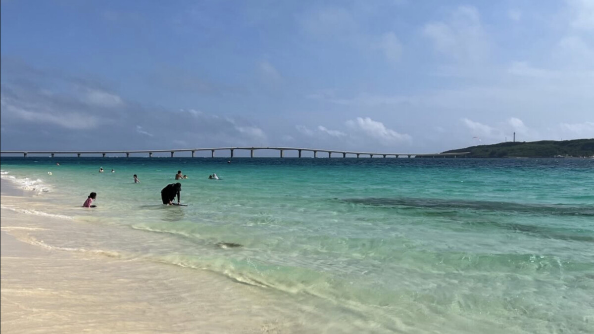 Yonaha Maehama on Miyako, clear pale shallows and white sand with swimmers and Kurima Bridge in the distance