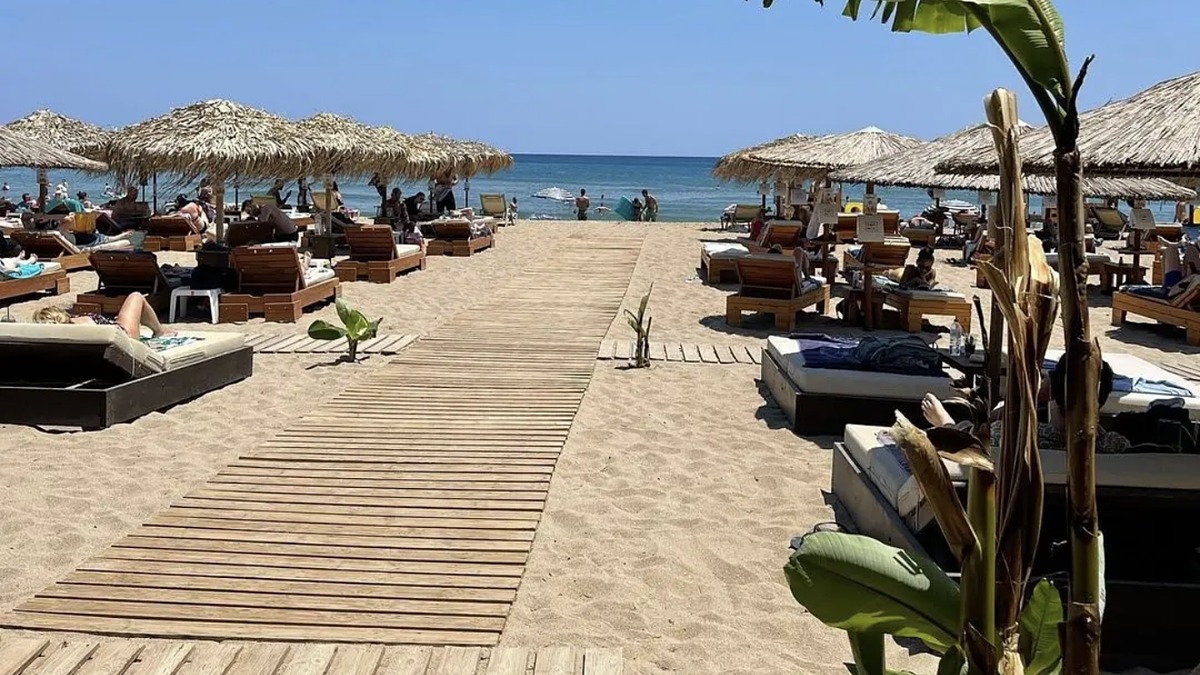 A beach club with thatched umbrellas and sunbeds on the golden sand at Tsampika Beach, Rhodes