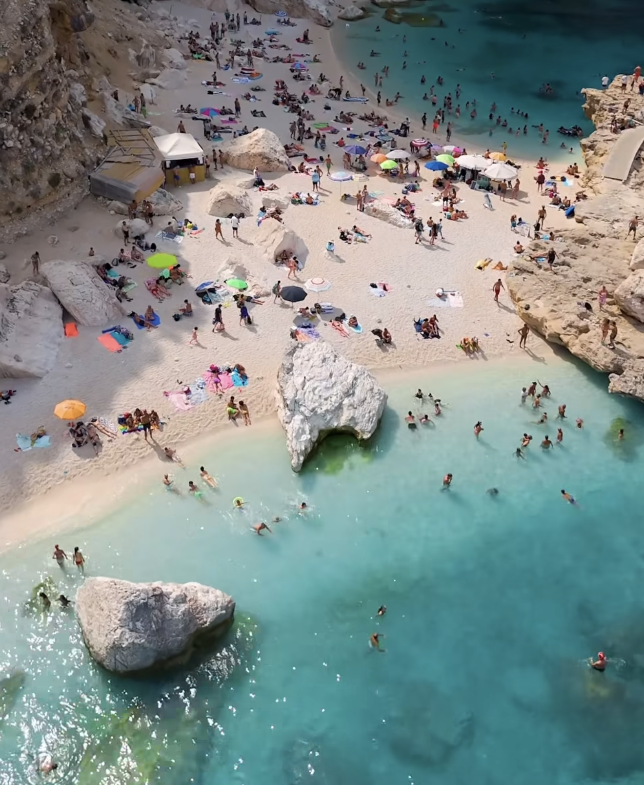 The white pebbles and big limestone boulders in the turquoise shallows at Cala Mariolu, Sardinia