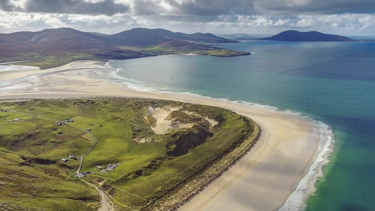 Luskentyre's vast tidal sand flats at low tide with a channel of turquoise water and machair dunes on the Isle of Harris